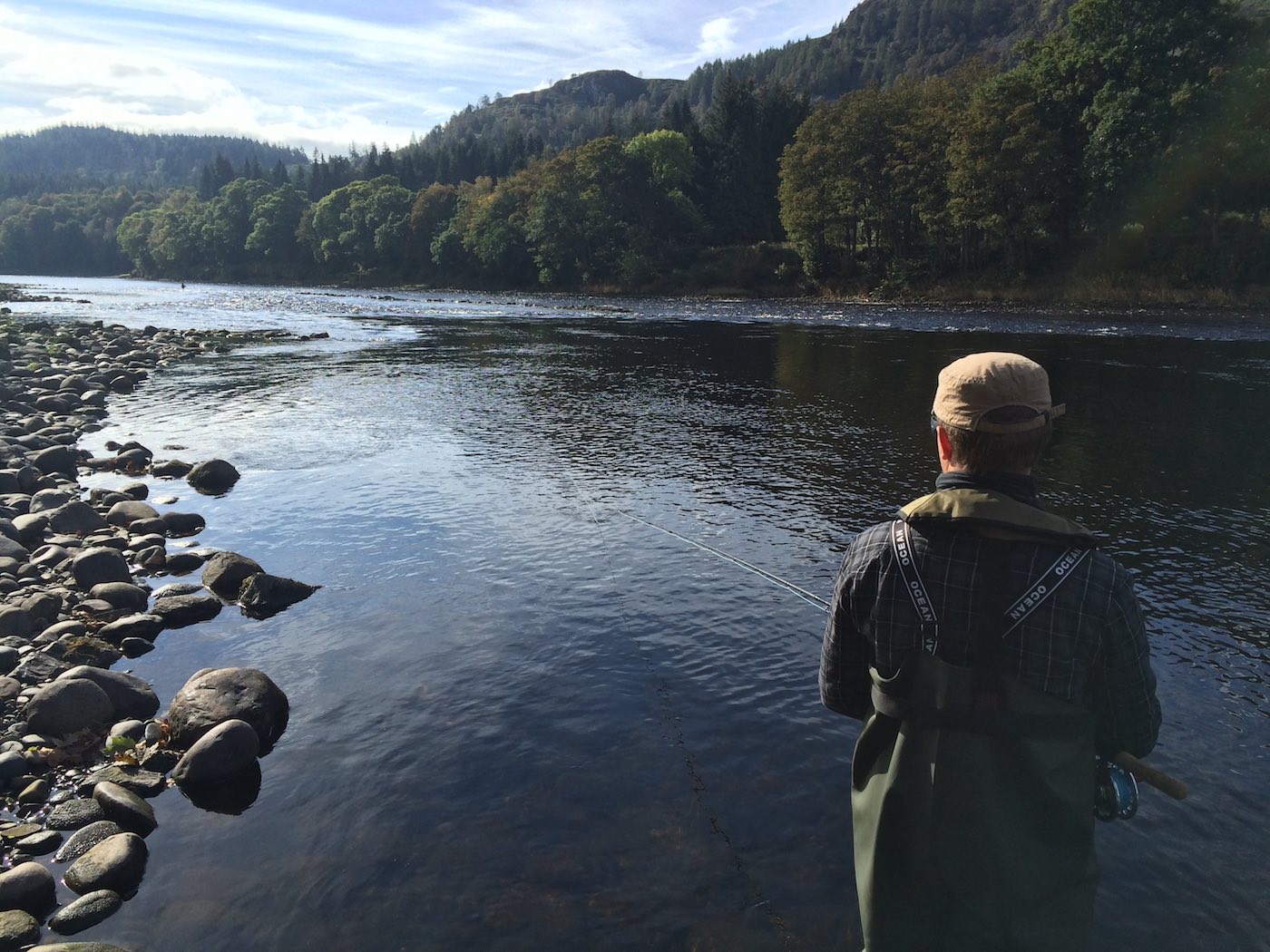 Often dark glassy water patches like this are also good salmon holding locations. This was one such salmon holding spot at the Trap Pool of the River Tay near Dunkeld. This salmon fishing trip fly fisher was just approaching the hot spot when his River Tay salmon fishing guide captured this lovely photograph.