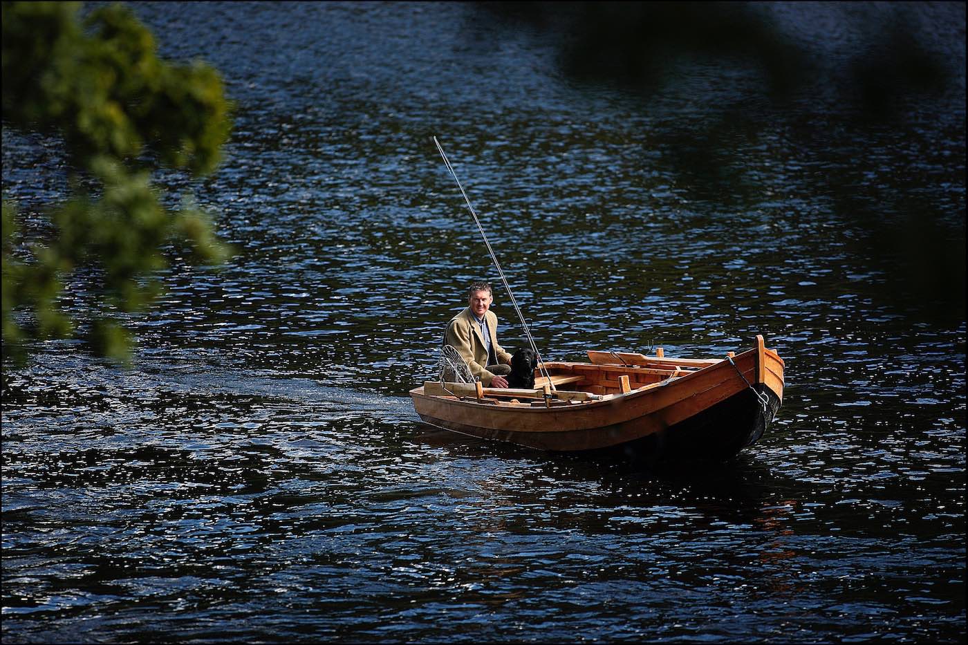 This fine shot of professional Scottish salmon guide Jock was taken in the Cottar Pool of the River Tay near Dunkeld and was taken by professional Glasgow based photographer Peter Sandground for the Glasgow Herald Magazine. Jock's black labrador is sitting in the bow of the boat.