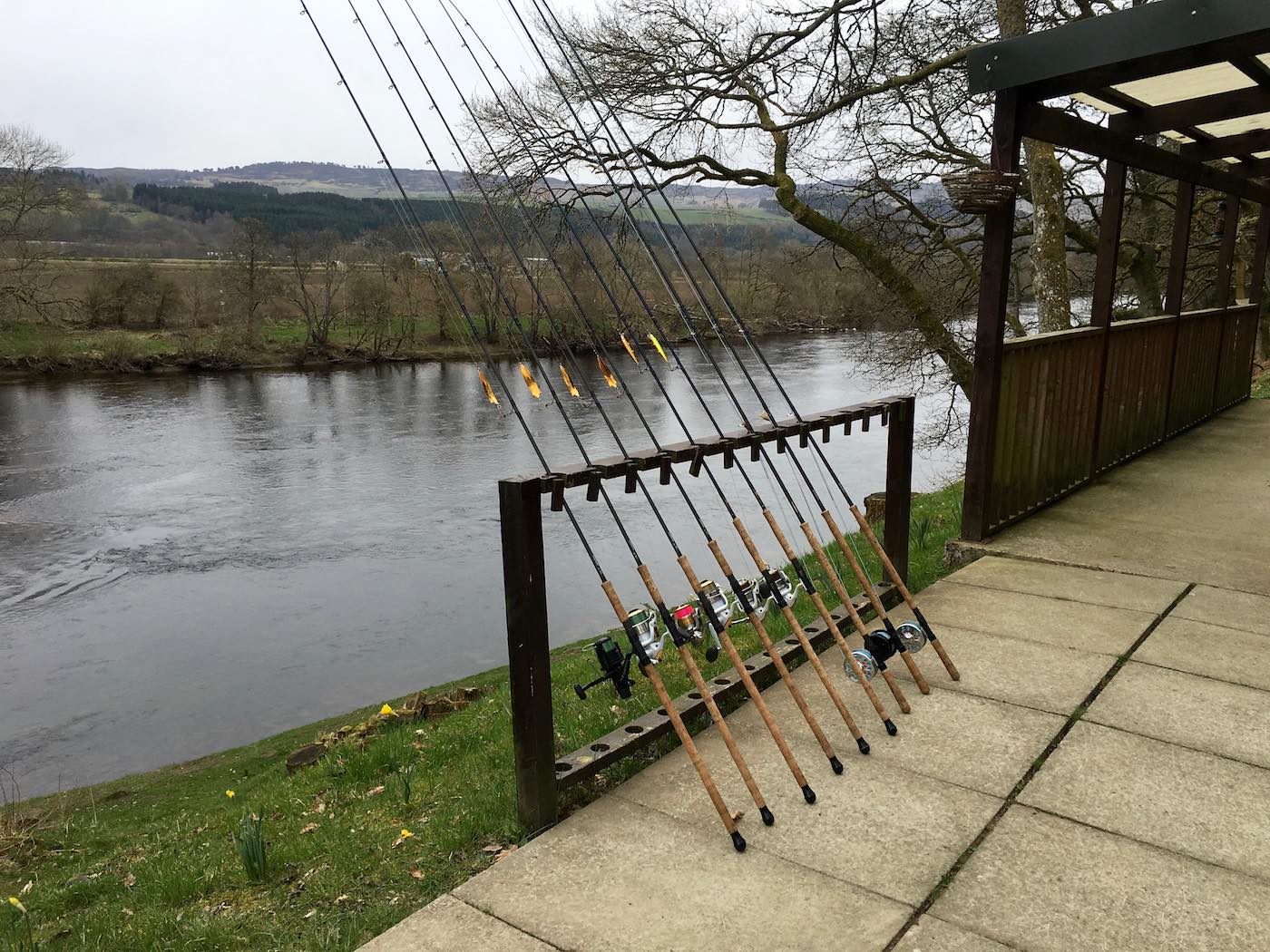 Here's a perfect line up of River Tay spin fishing rods on the rod rack outside of the Upper Kinnaird salmon fishing hut. This shot was taken at 8am in the morning by the salmon guide before the salmon fishing trip guests turned up for their day on the river.  You can see the ripple in the river behind the rods which is a serious salmon lie.