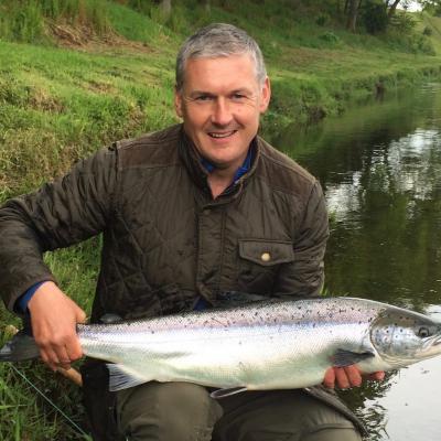 Jock Monteith is a well known professional salmon fishing tour organiser in Scotland and leading professional salmon fishing guide. Jock is holding a perfect fresh run 14lbs Summer salmon in this shot at the Daffodil Lie Pool of the River Tay's Kinnaird Beat which he hooked after a few casts while testing out a salmon fishing trip client's new fly rod .