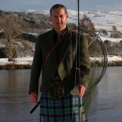 This photograph of professional Scottish salmon fishing guide Jock Monteith was captured by TV producer Chris Webster outside Ferry Cottage on the Kinnaird Estate of the River Tay in Perthshire. You can see the snow clad hills and riverbanks in the background.