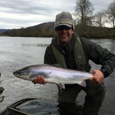 This happy American salmon fishing guest landed this perfect salmon on a cold & dull early Spring day with the assistance of myself as his salmon guide. The leader material we were using was good old 'time tested' Maxima Chameleon which has always been my leader material of choice. This salmon fishing guest has a warm hat on and a life jacket too for wading safety reasons.