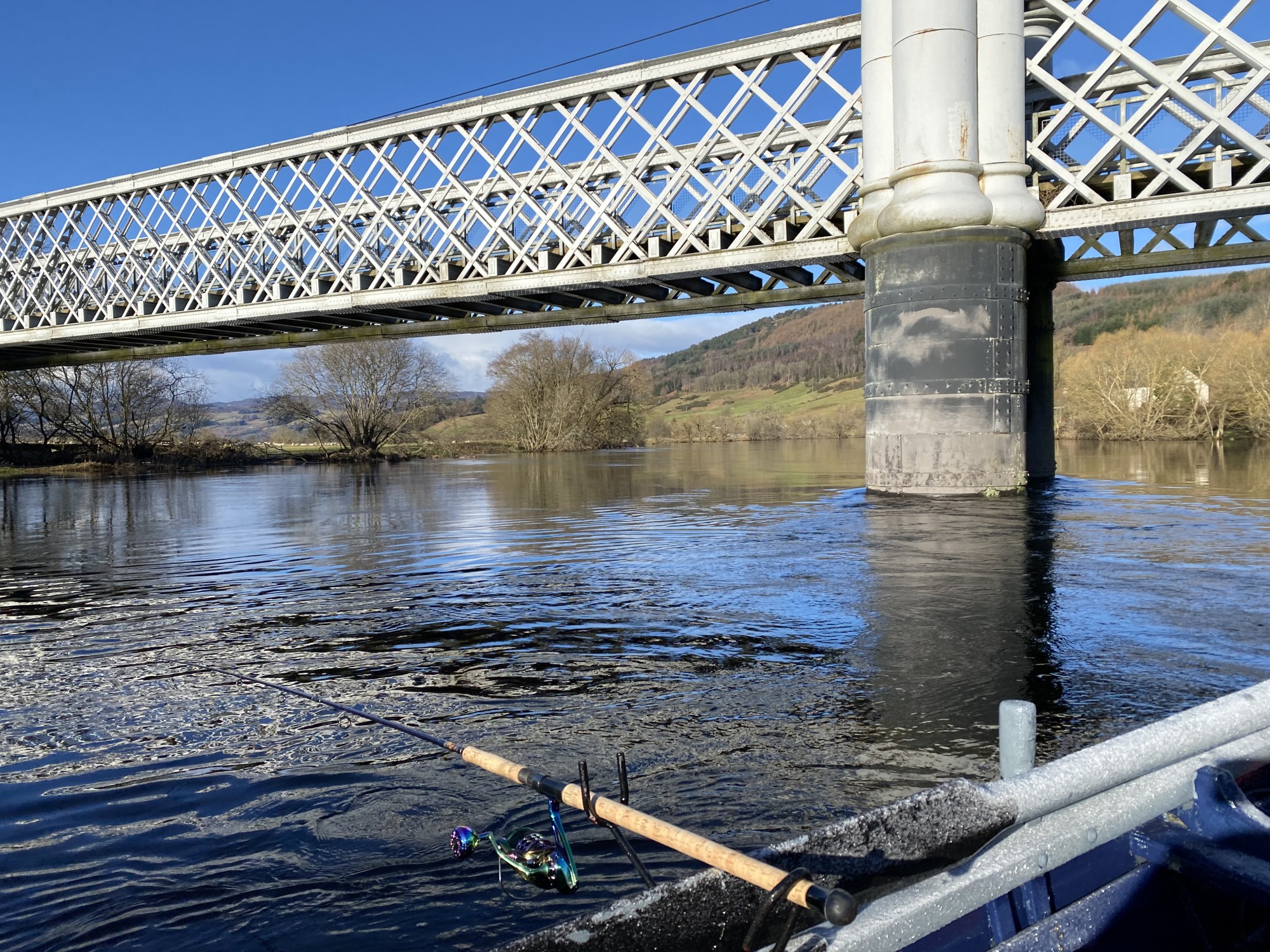 Here's a River Tay coble clinker built salmon boat being used for harling on the Kinnaird Beat. There's a good salmon lie directly under the Logierait Bridge that you can see in this picture. Harling is a River Tay boat fishing method than fishes 3 or more lures at once. I took this shot in during high water in February.